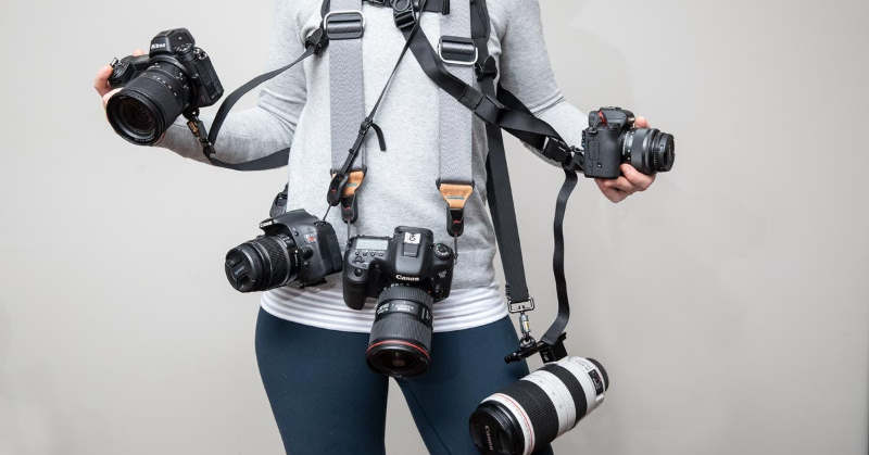 a woman carrying a lot of cameras